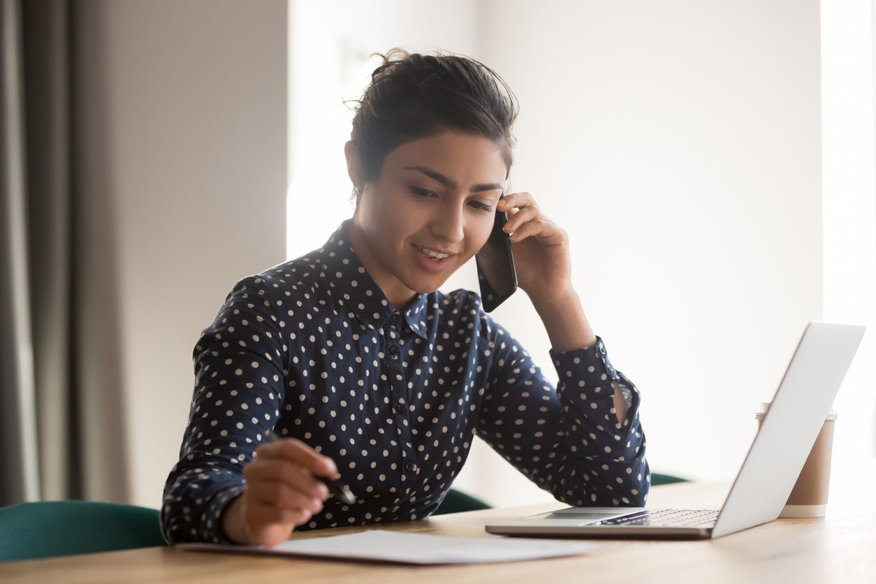 woman talking on the phone in front of her laptop